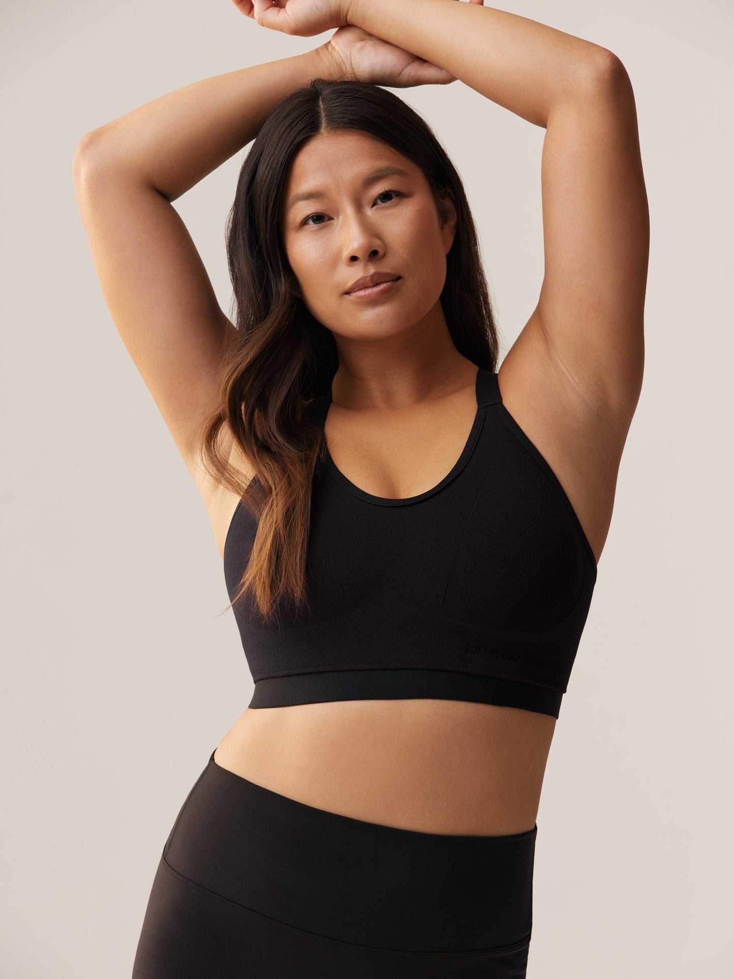 Lachend model met armen omhoog in de zwarte Soft Revolt Milou Active Bra: naadloze high support sport-bh voor vollere cupmaten die maximale bewegingsvrijheid en comfort biedt.